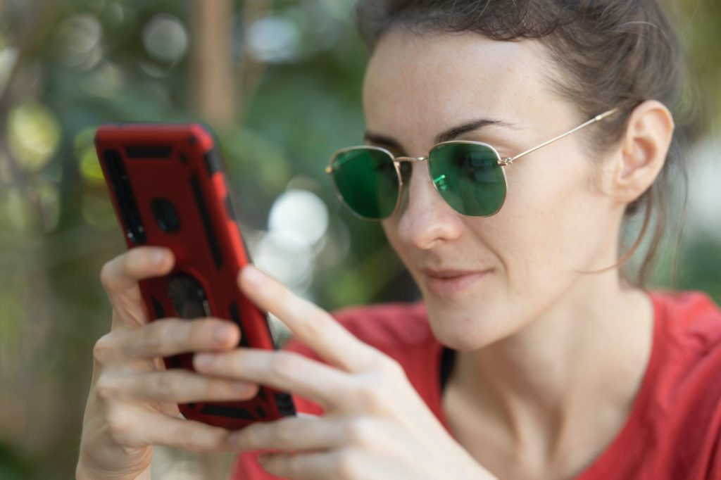 woman holding smartphone and wearing sunglasses
